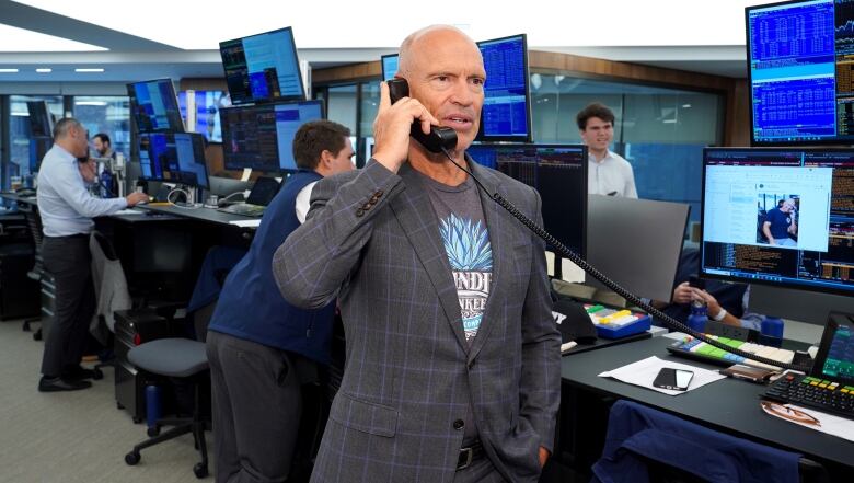 Man stands while holding phone. 