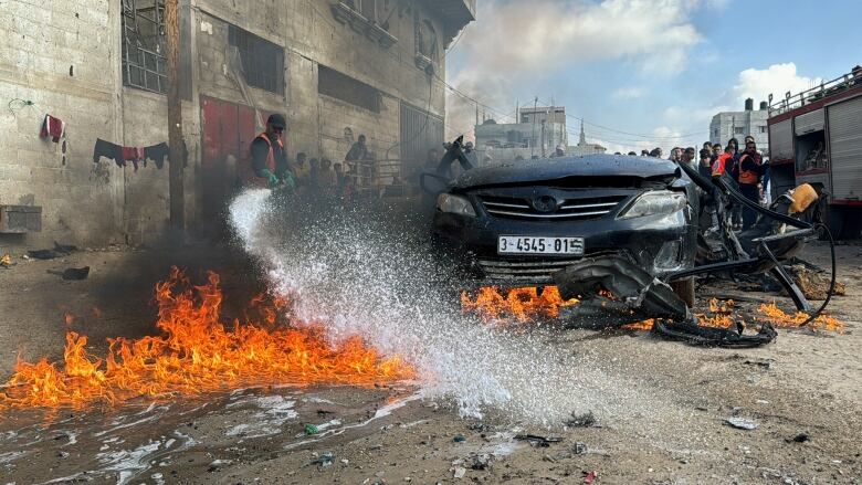 A firefighter extinguishes a burning car.