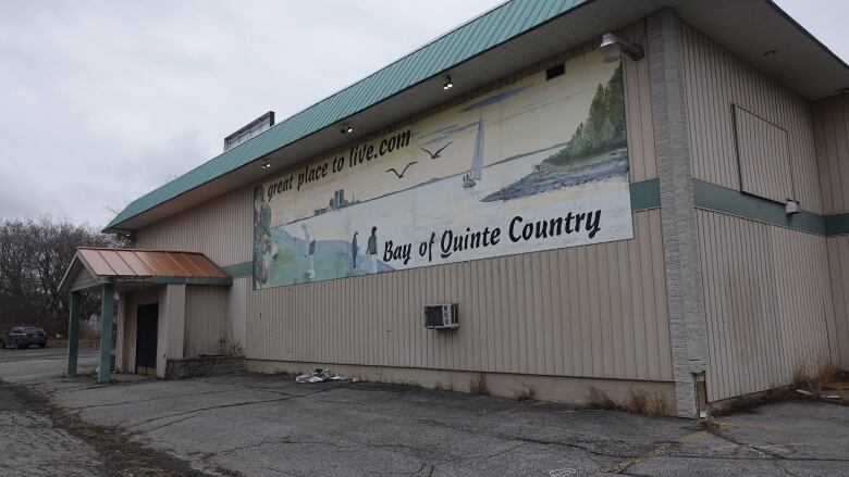 A large, beige building with a massive mural on one wall announcing 