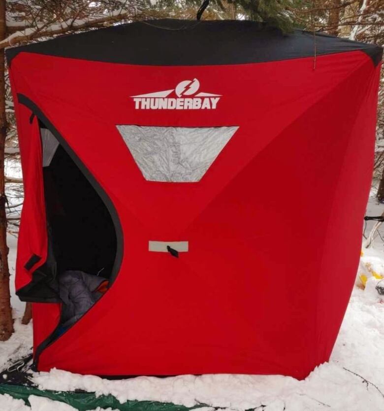 An ice-fishing tent set up on a platform in the snow.