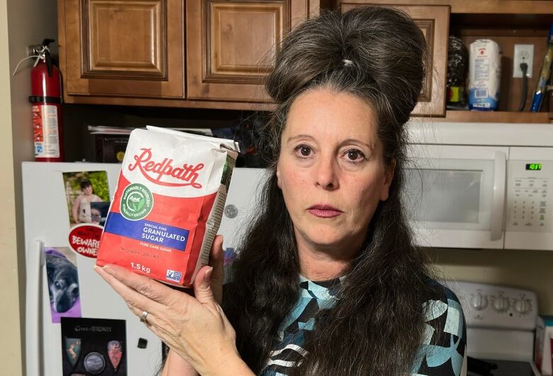 Janet Dermody holding up a bag of 1.5 kg Redpath sugar. 