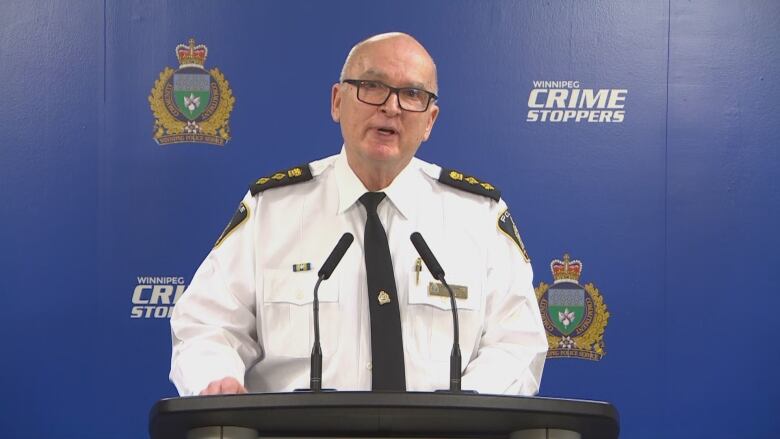 A man in a police uniform stands behind a podium.