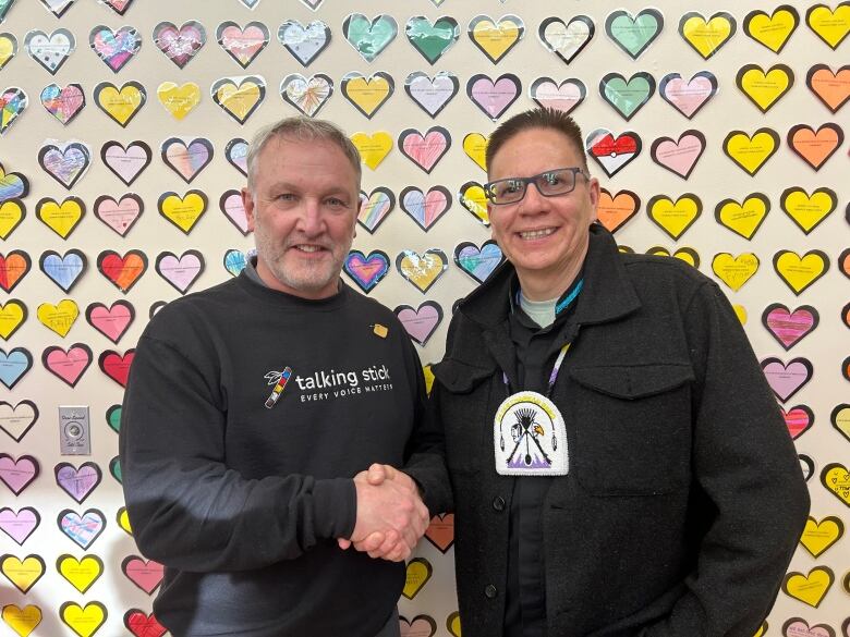 Two men pose while shaking hands.