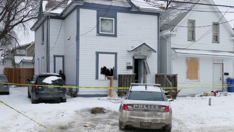 A police car is parked outside a home taped off with yellow police tape.