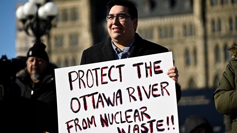 A man holds a sign on Parliament Hill.