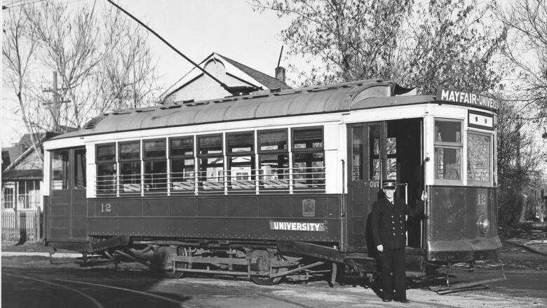 An old black and white photo shows a man in a uniform standing in front of a streetcar that is labelled 