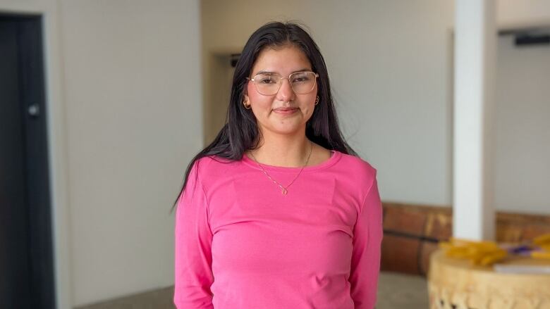 A woman in a pink shirt and glasses 