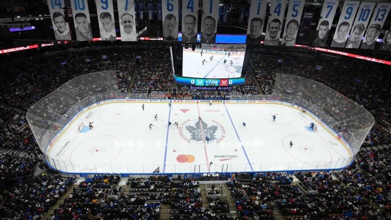 A large crowd watches a hockey game inside an arena.