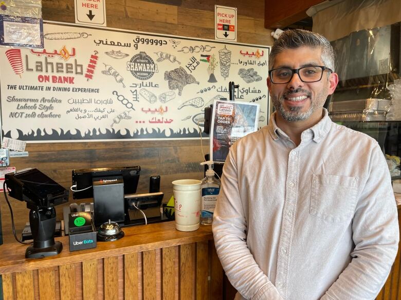 A shawarma shop owners poses in a restaurant.