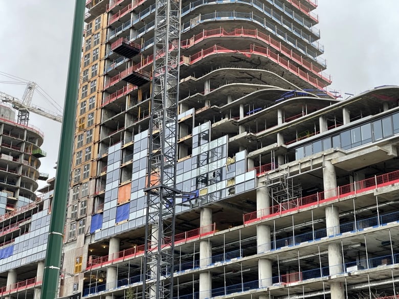 A building is seen with significant damage along its side, with a crane in the foreground.