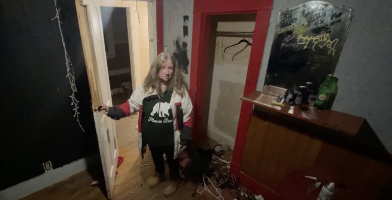 A woman stands in a destroyed room.