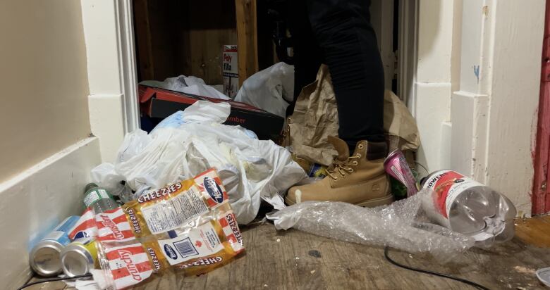 A woman stands in a pile of garbage.