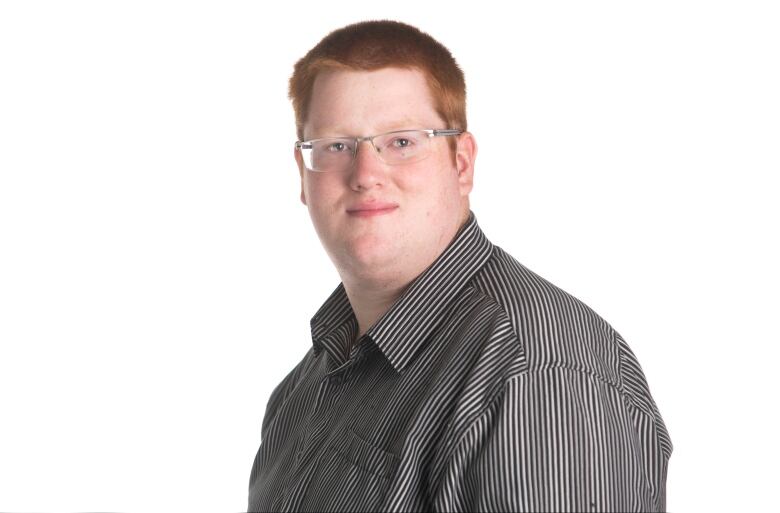 A man with glasses and red hair in front of a white background.