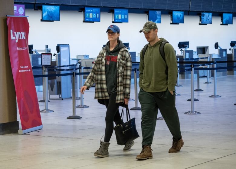 a man and a woman walk along an airport hallway