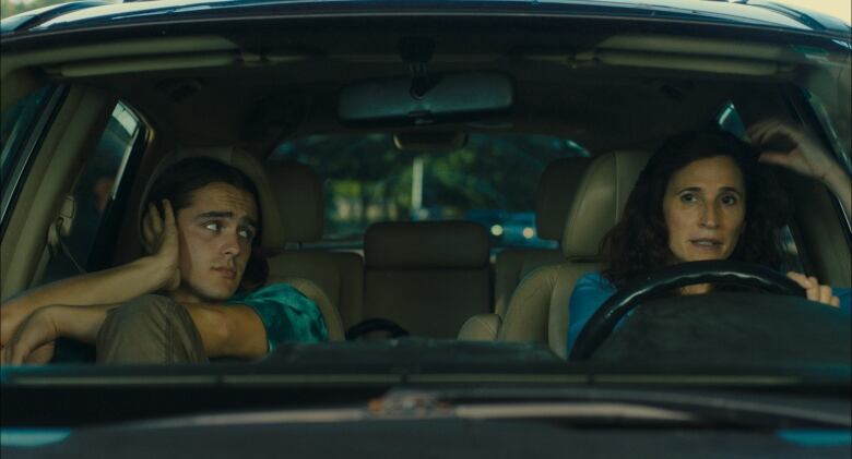 Charlie Gillespie's Gage and Michaela Watkins' Suze are shown in a car, with Suze driving. 