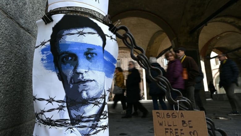 People in Milan, Italy walk past a poster of late Russian opposition leader Alexei Navalny.