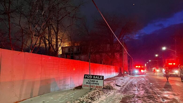 A building on fire. Fire trucks can bee seen parked beside it.