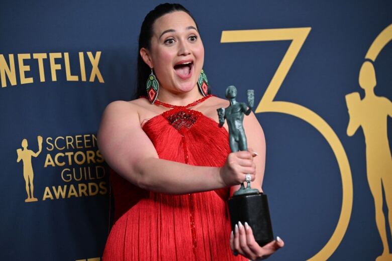 Actress Lily Gladstone poses with an SAG award for best female actor in a movie. 