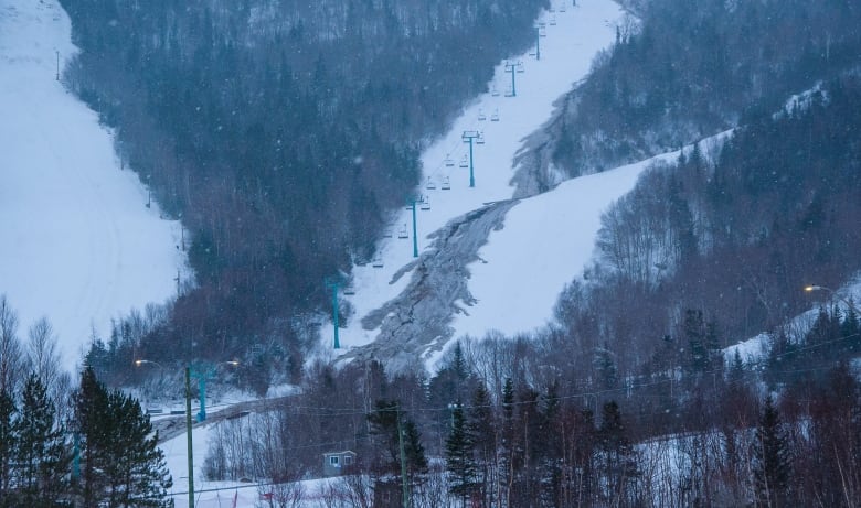 A ski kill has a large grey track where snow has rapidly melted.