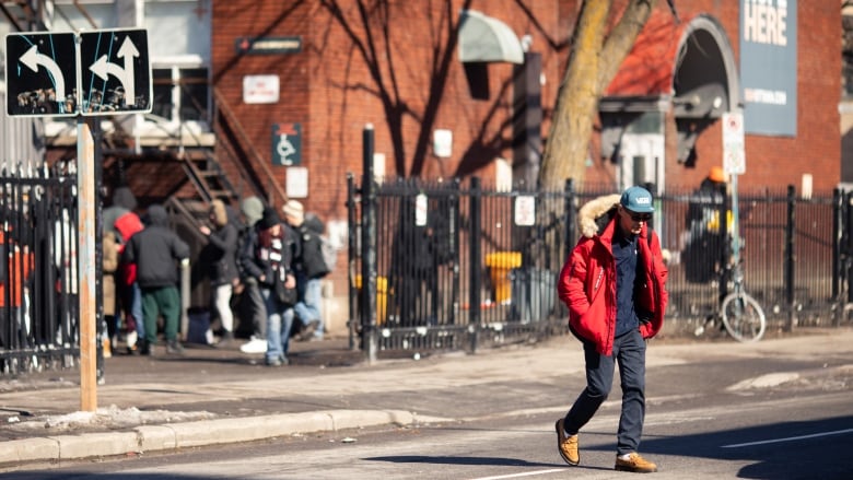 A man walking across the street away from a food kitchen.