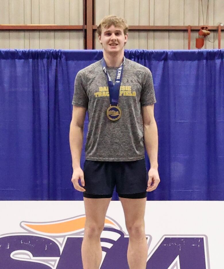 A young man wearing a medal poses for a photo.