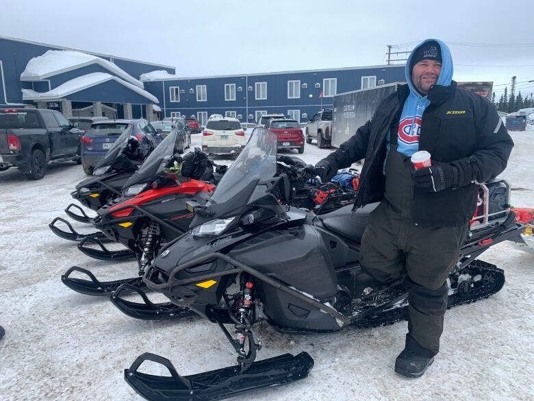 A man kneels on a snowmobile.