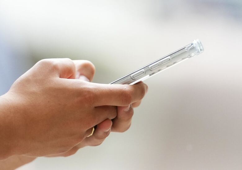 Photo showing a pair of hands using a cell phone.