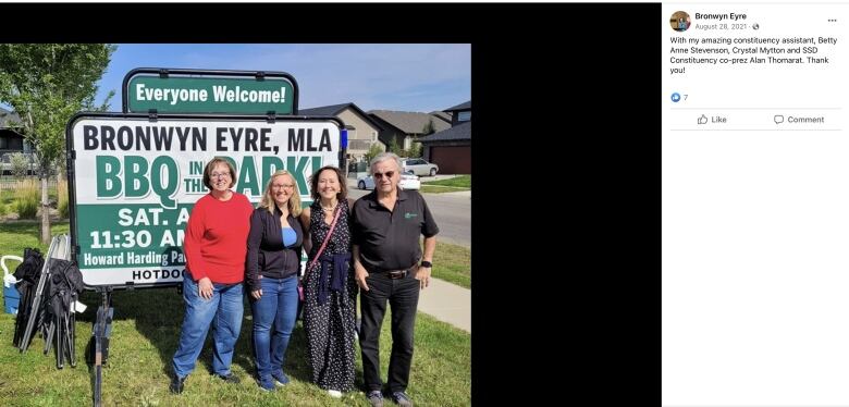 An image of four people standing in front of a sign 