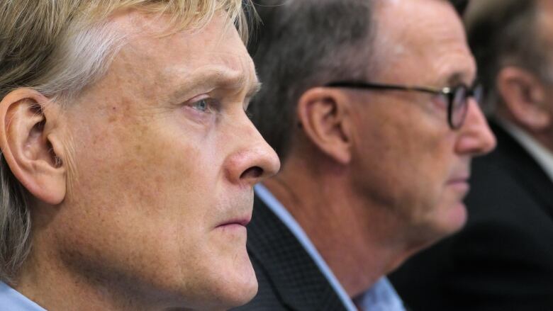 Close ups of the faces of two men, in side profile.