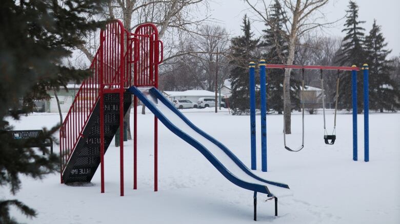 A slide and a swing set stand in a snowy Parkdale Park in Regina. 