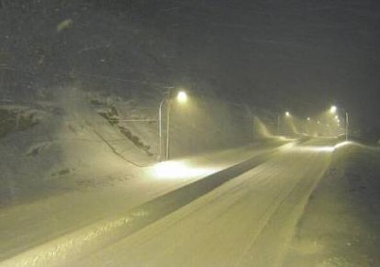 A highway in half-light with snow acumulating.