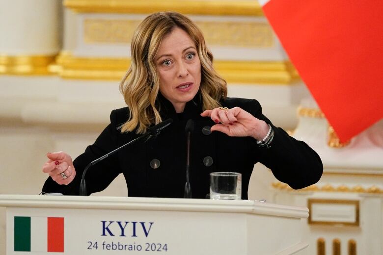 A woman with hands raised stands behind a podium