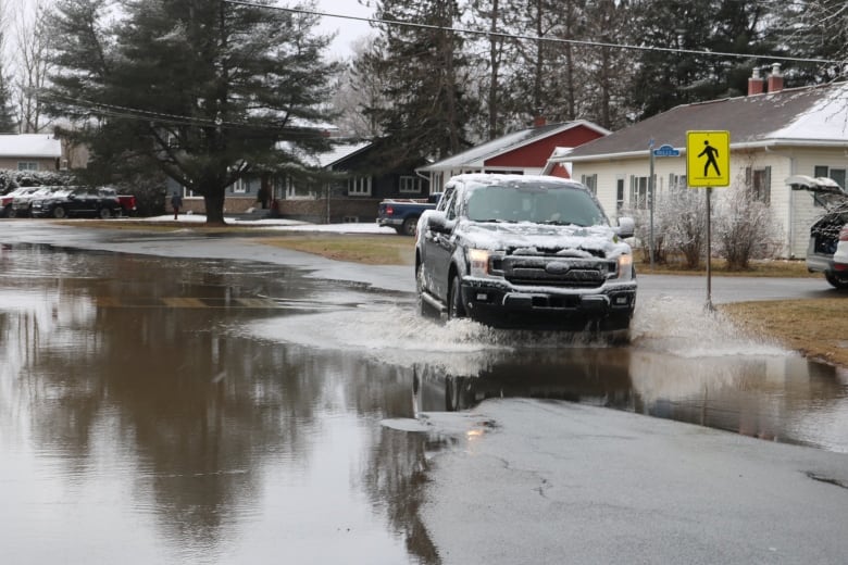 A snowy vehicle drives through water