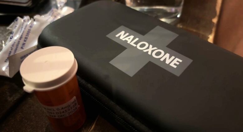 A black case with a cross on the front and the word 'naloxone' printed across.