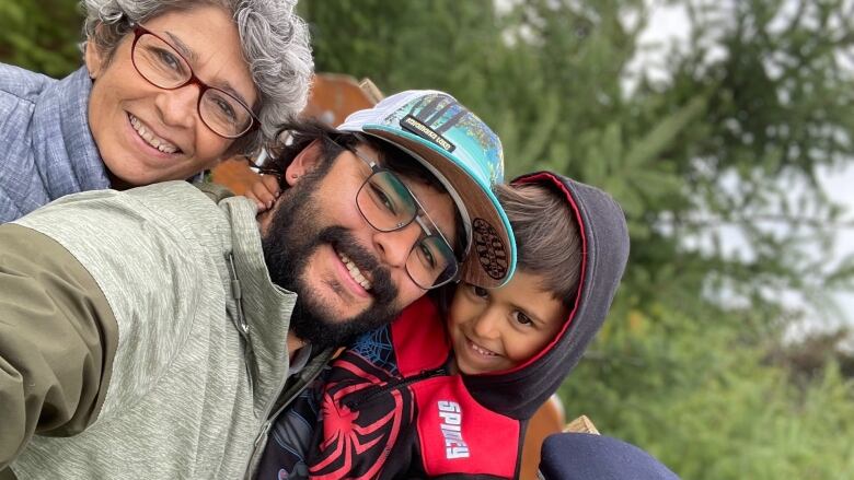 Two grandparents pose for a photo with their son and his young son.