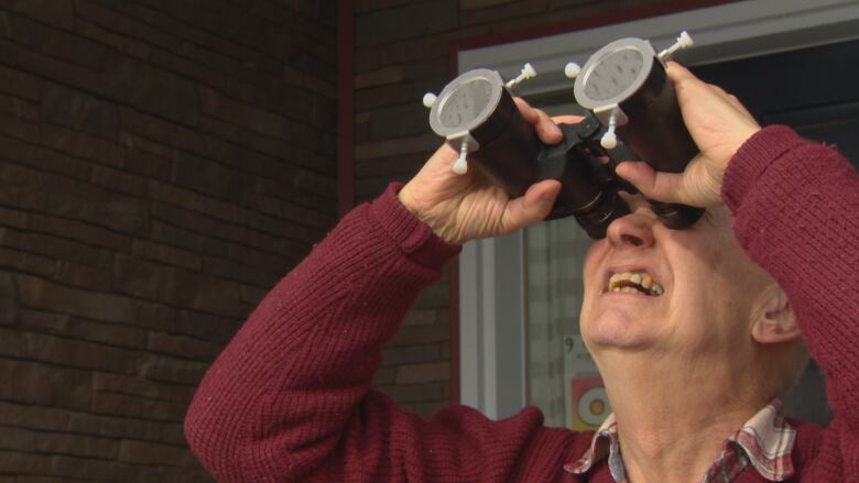 A man looking through some binoculars.