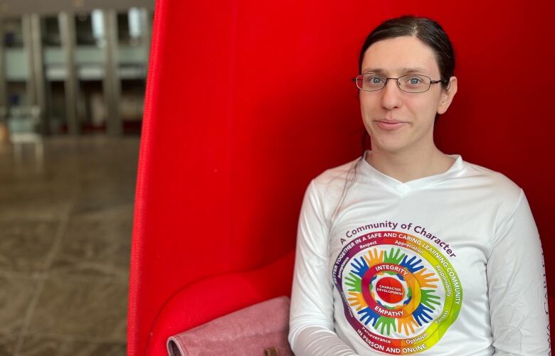 A school trustee poses for a photo while sitting in a red chair.