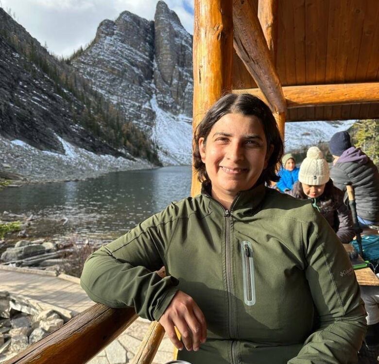 Photo of person sitting at table with mountain lake view in background