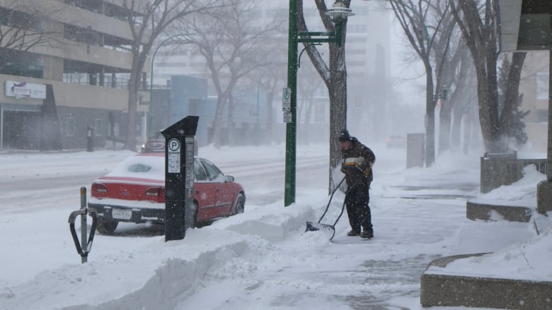 a person is shovelling snow in downtown saskatoon