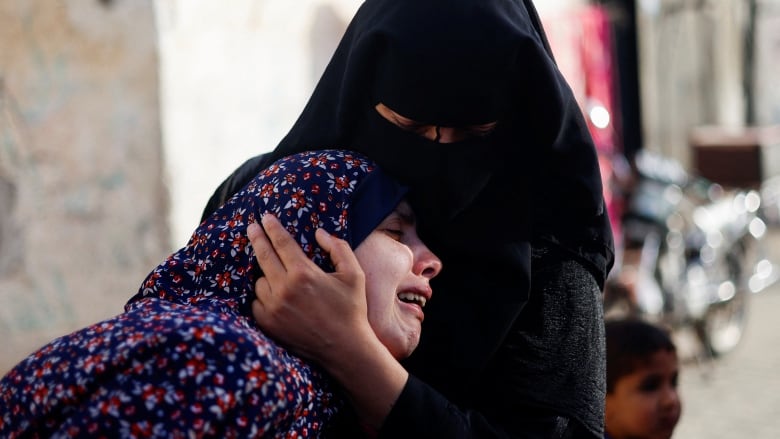 A woman cries while being held by another woman. 