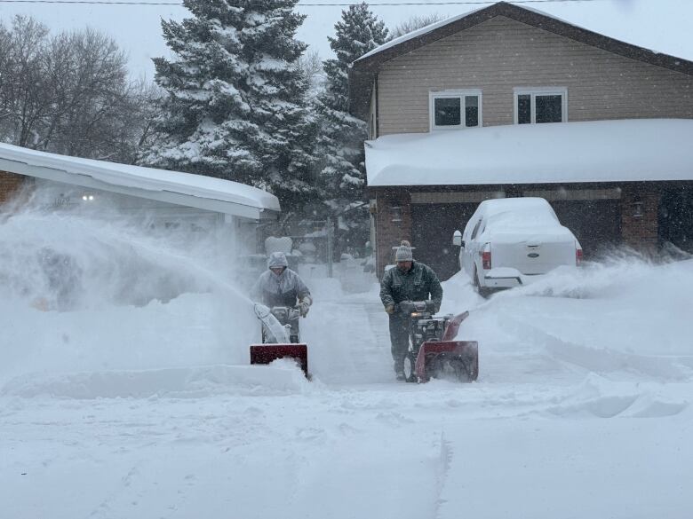 Two Saskatoon residents clearing snow from their properties after the winter storm.