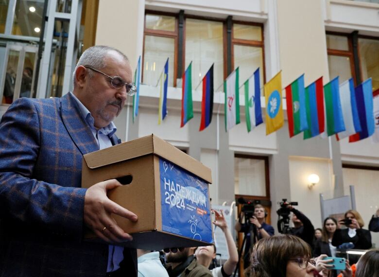 Boris Nadezhdin, a representative of Civil Initiative political party, carries a box containing forms with collected signatures as he visits an office of the Central Election Commission office in Moscow on January 31, 2024. 