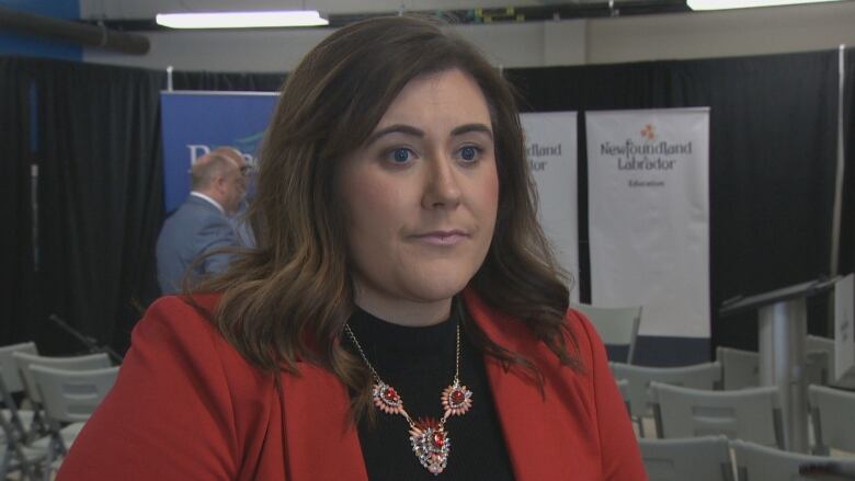 A woman with dark hair wears a bright red jacket. 