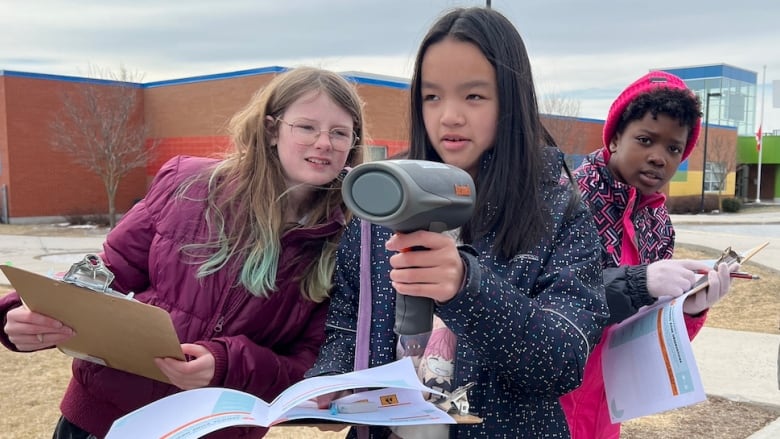 Students operate operate a speed radar gun in front of their elementary school