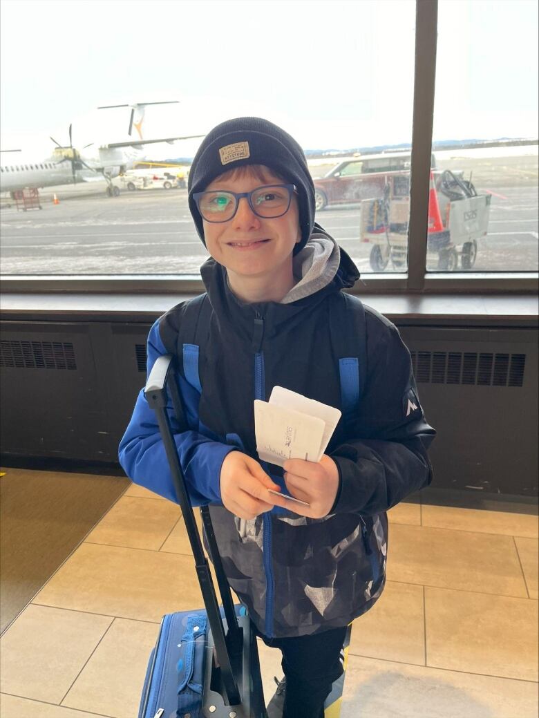 Little boy in an airport with a suitcase.