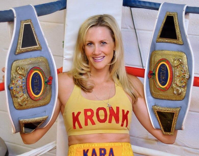 Kara Ro holds up championship belts.