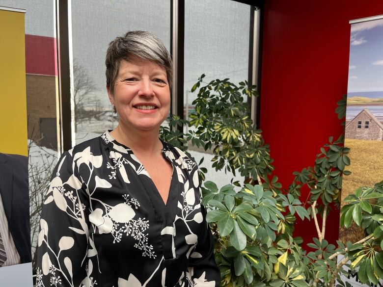 Woman standing beside plant.