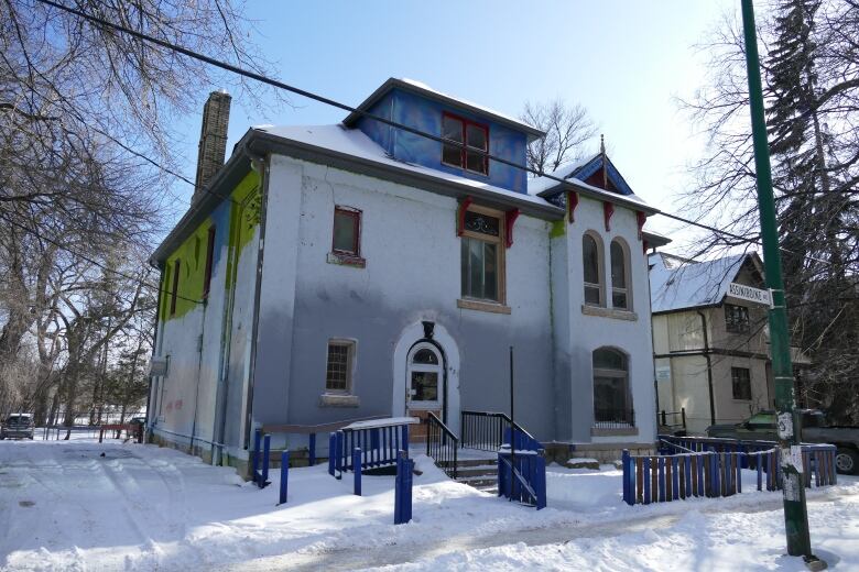 A two-storey building brick building with a blue fence. 