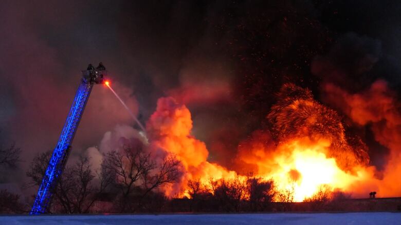 Flames and smoke light up the night sky.