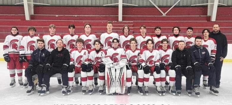 A team of hockey players pose on the ice. 